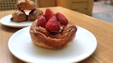 Üzerine taze çilek konmuş İtalyan ekmeği. Kahverengi bir masada paslanmaz çelik bıçakla kesilmiş..