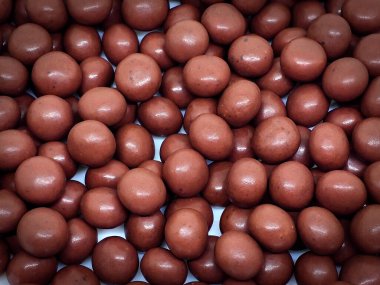 Pastel şeftali arka planında beyaz bir tabakta çikolata kaplı bisküvi yığını. Tatlı atıştırmalık.