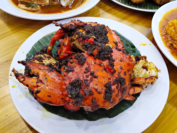 Копченый краб или кепитинг Asap на индонезийском языке готовится с черными специями приправы на основе бананового листа подается на белой тарелке.