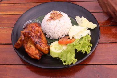 Izgara tavuk, sebze ve soslu bir tabak pilav.