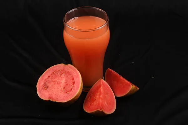 Siyah cam zemin üzerinde taze kırmızı greyfurt suyu