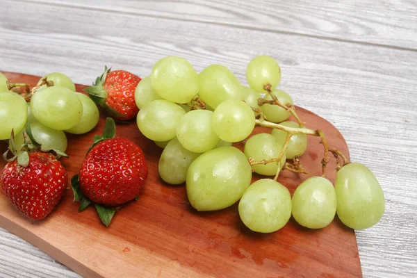 Frische Grüne Trauben Und Erdbeeren Auf Holzteller — Stockfoto
