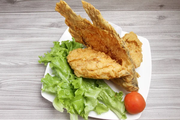 Fried fish with vegetables  sauce on plate