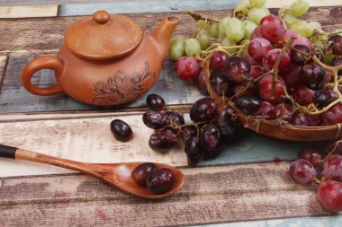 Tahta bir kasede üzüm ve masada bir bardak şarap..