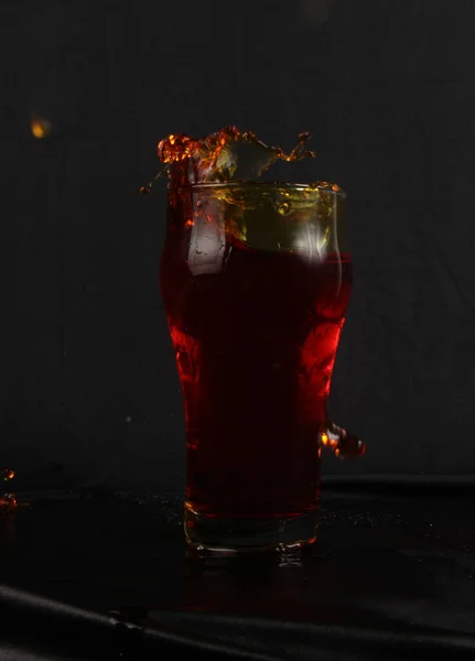 用红色液体在杯子里加冰 在黑色背景上 — 图库照片