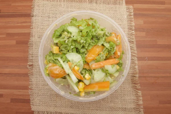 vegetable salad in a plastic container on a wooden background