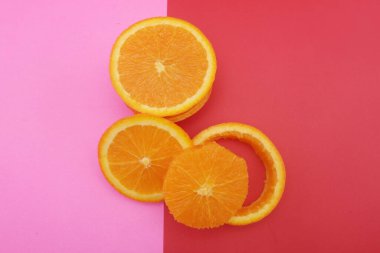Pembe ve turuncu arka planda dilimlenmiş portakal ve greyfurt..