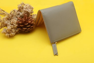 Altın kalemli kahverengi cüzdan ve sarı arka planda bir defter.