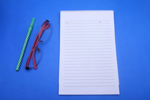 paper, notebook, pen and clips on a black background