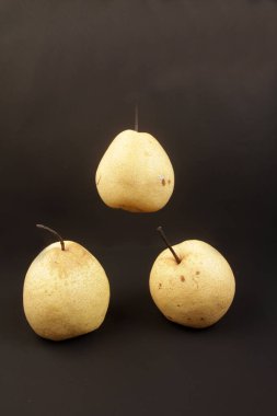 Siyah zemin üzerinde taze sarı armutlar.