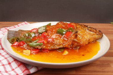 Ahşap zemin üzerinde sebzeli fırında balık.