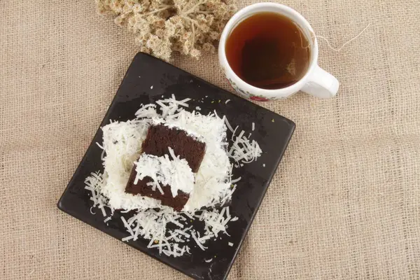 black forest cake with grated chese and a cup of hot tea
