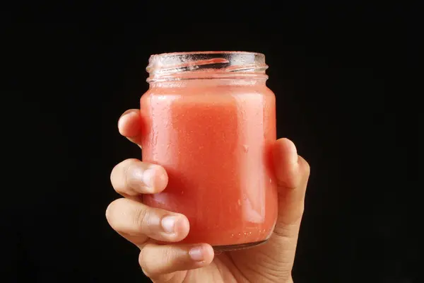 hand holding a glass of guava juice