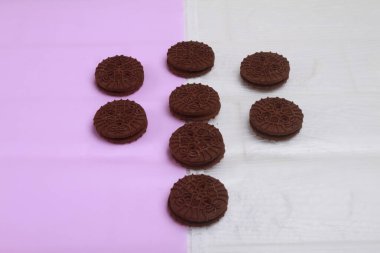 Nefis çikolatalı kurabiyelerin ve pembe arka planda beyaz çikolatanın üst görüntüsü.