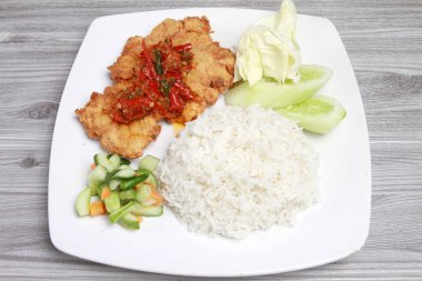 Bir tabak pilav, kızarmış tavuk, sebze ve sos.