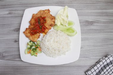 Bir tabak pilav, kızarmış tavuk, sebze ve sos.