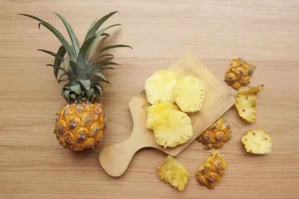 pineapple slices and slices of wood on wooden cutting board, top view