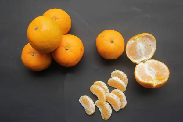 fresh mandarins and slices of mandarins on a black background. citrus fruit.