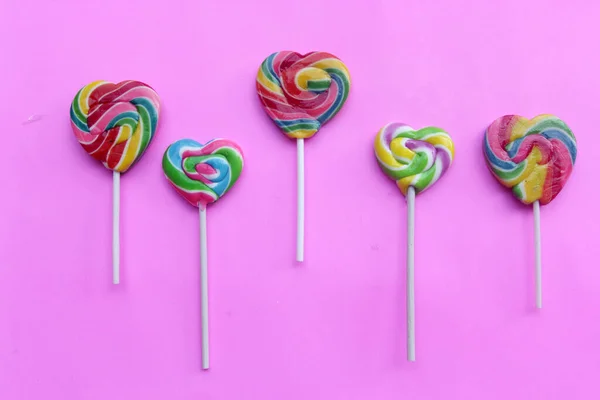 Pembe arka planda renkli lolipoplar.