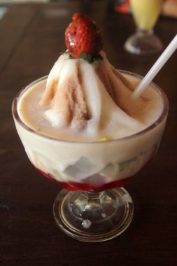 Bardakta dondurma ve ahşap masada çilek..