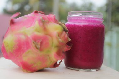 bir bardak ejderha meyve suyu ve ejderha meyvesi ahşap masada izole