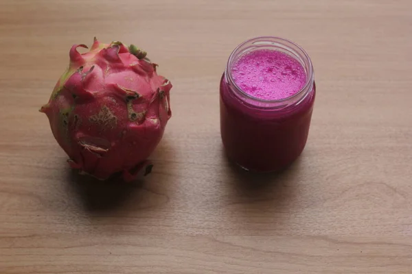 a glass of dragon fruit juice and dragon fruit isolated on wooden table