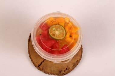 Beyaz arka planda meyveleri olan plastik bir kap