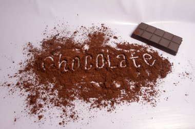 Kakao tozu ve koyu beyaz arka planda çikolata.