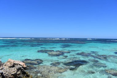 Rottnest Adası, Batı Avustralya. Doğadaki Dinginlik: berrak mavi su, kayalık sahil ve güneşli gökyüzü ile sakin koy.