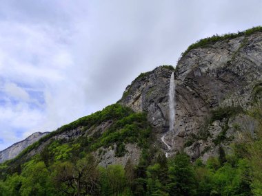 Arpenaz waterfall, one of France highest cascade in Haute Savoie in springtime with impressif cliff of Giffre Massif mountain, alpine landscape clipart