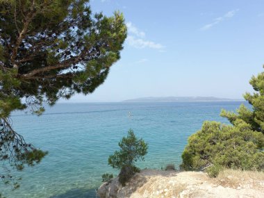 Ağaçlı güzel bir deniz manzarası ve Hırvatistan 'da beyaz bulutlu berrak bir gökyüzü.