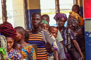 Abuja, Nijerya - 10 Şubat 2021: Afrikalılar kırsal kesimde oturuyor, kuyruğa giriyor ve ücretsiz tıbbi bakım ve ilgi bekliyorlar. Seçimlerde oy kullanmak için kaydolurlar. Siyasi Kampanya Egzersizi