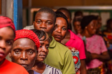 Abuja, Nijerya - 10 Şubat 2021: Afrikalılar kırsal kesimde oturuyor, kuyruğa giriyor ve ücretsiz tıbbi bakım ve ilgi bekliyorlar. Seçimlerde oy kullanmak için kaydolurlar. Siyasi Kampanya Egzersizi