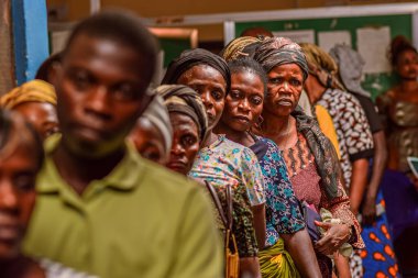Abuja, Nijerya - 10 Şubat 2021: Afrikalılar kırsal kesimde oturuyor, kuyruğa giriyor ve ücretsiz tıbbi bakım ve ilgi bekliyorlar. Seçimlerde oy kullanmak için kaydolurlar. Siyasi Kampanya Egzersizi