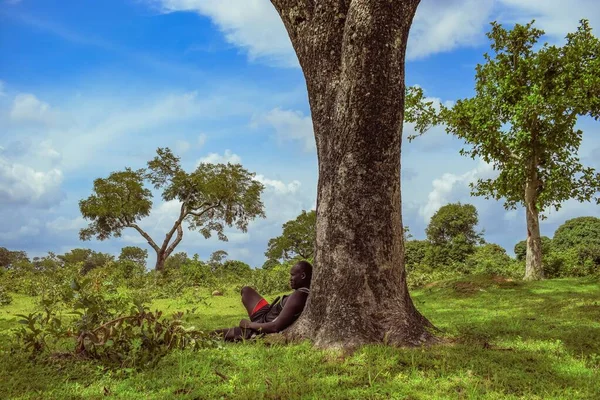 stock image Plateau, Nigeria - April 5, 2023: African Man Taking a Rest in Nature After a Long Day Farming. Beautiful Scenery of the African Woods.