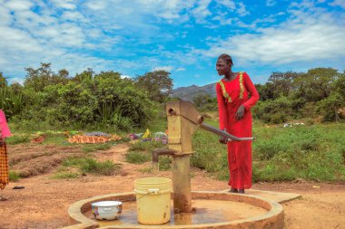 Karara, Nasarawa Eyaleti, Nijerya - 5 Mayıs 2021: Afrika 'da Kırsal Toplulukta Yeni Yapılandırılmış Hint Eli Pompa Borewell Kullanan Afrcian Kadın. Bir Topluluk Su Deliği 'nden Akan Su