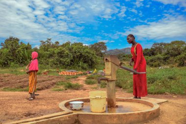 Karara, Nasarawa Eyaleti, Nijerya - 5 Mayıs 2021: Afrika 'da Kırsal Toplulukta Yeni Yapılandırılmış Hint Eli Pompa Borewell Kullanan Afrcian Kadın. Bir Topluluk Su Deliği 'nden Akan Su