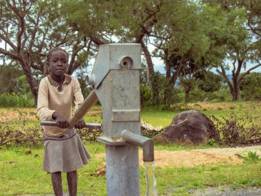 Karara, Nasarawa Eyaleti, Nijerya - 5 Mayıs 2021: Afrika 'da bir kırsal kesimde Hint El Pompası Borewell kullanan kız. Bir Topluluk Su Deliği 'nden Akan Su