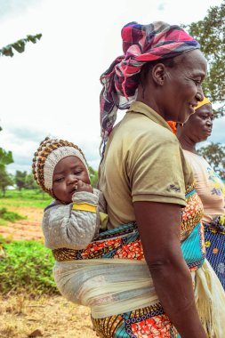 Karara, Nasarawa Eyaleti, Nijerya - 5 Mayıs 2021: Afrikalı Çocuk Portresi. Anne oğlunu askıda taşıyor. 