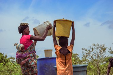 Abuja, Nijerya - 8 Ekim 2022: Afrikalılar su getiriyor. Afrika toplumunda Temiz Su Çözümü. Kova içinde Mutlu Afrika Getiren Suyu.