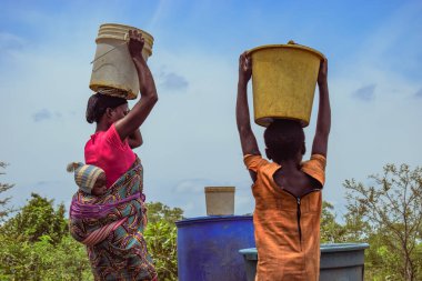 Abuja, Nijerya - 8 Ekim 2022: Afrikalılar su getiriyor. Afrika toplumunda Temiz Su Çözümü. Kova içinde Mutlu Afrika Getiren Suyu.