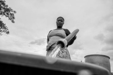 Abuja, Nigeria - October 8, 2022: African woman Fetching Water. Clean Water Solution in African Community. Happy African Fetching Water in a Bucket clipart