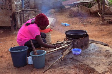 Opialu, Benue State - 6 Mart 2021: Odun odunuyla dışarıda yemek pişiren Afrikalı Kadın
