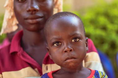 Opialu, Benue State - 6 Şubat 2022: Annesi kameraya bakarken Afrikalı Çocuk