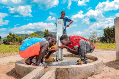 Abuja, Nijerya - 2 Ağustos 2021: Kırsal bir toplulukta güneşin altında temiz suyla oynarken mutluluk ve kahkaha ifade ederken eğlenen Afrikalı çocuklar. Neşeli ve Minnettar Çocuklar