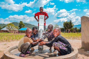 Abuja, Nijerya - 2 Ağustos 2021: Kırsal bir toplulukta güneşin altında temiz suyla oynarken mutluluk ve kahkaha ifade ederken eğlenen Afrikalı çocuklar. Neşeli ve Minnettar Çocuklar