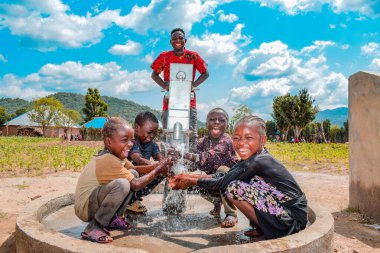 Abuja, Nijerya - 2 Ağustos 2021: Kırsal bir toplulukta güneşin altında temiz suyla oynarken mutluluk ve kahkaha ifade ederken eğlenen Afrikalı çocuklar. Neşeli ve Minnettar Çocuklar
