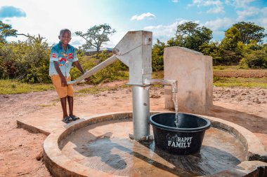 Abuja, Nijerya - 2 Ağustos 2021: Kırsal bir toplulukta güneşin altında temiz suyla oynarken mutluluk ve kahkaha ifade ederken eğlenen Afrikalı çocuklar. Neşeli ve Minnettar Çocuklar