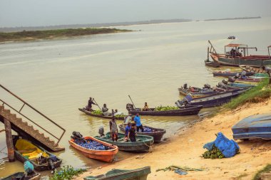 Delta State, Nijerya - 9 Aralık 2021 Nijer nehrinin kıyısında güzel bir Sunrise 'ı dengeleyen yerel kanolar yapıldı. Nehir kıyısında balıkçı tekneleri. Bir su yüzeyinde yansıma.