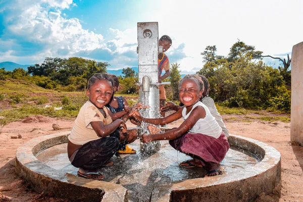 Abuja, Nijerya - 2 Ağustos 2021: Kırsal bir toplulukta güneşin altında temiz suyla oynarken mutluluk ve kahkaha ifade ederken eğlenen Afrikalı çocuklar. Neşeli ve Minnettar Çocuklar
